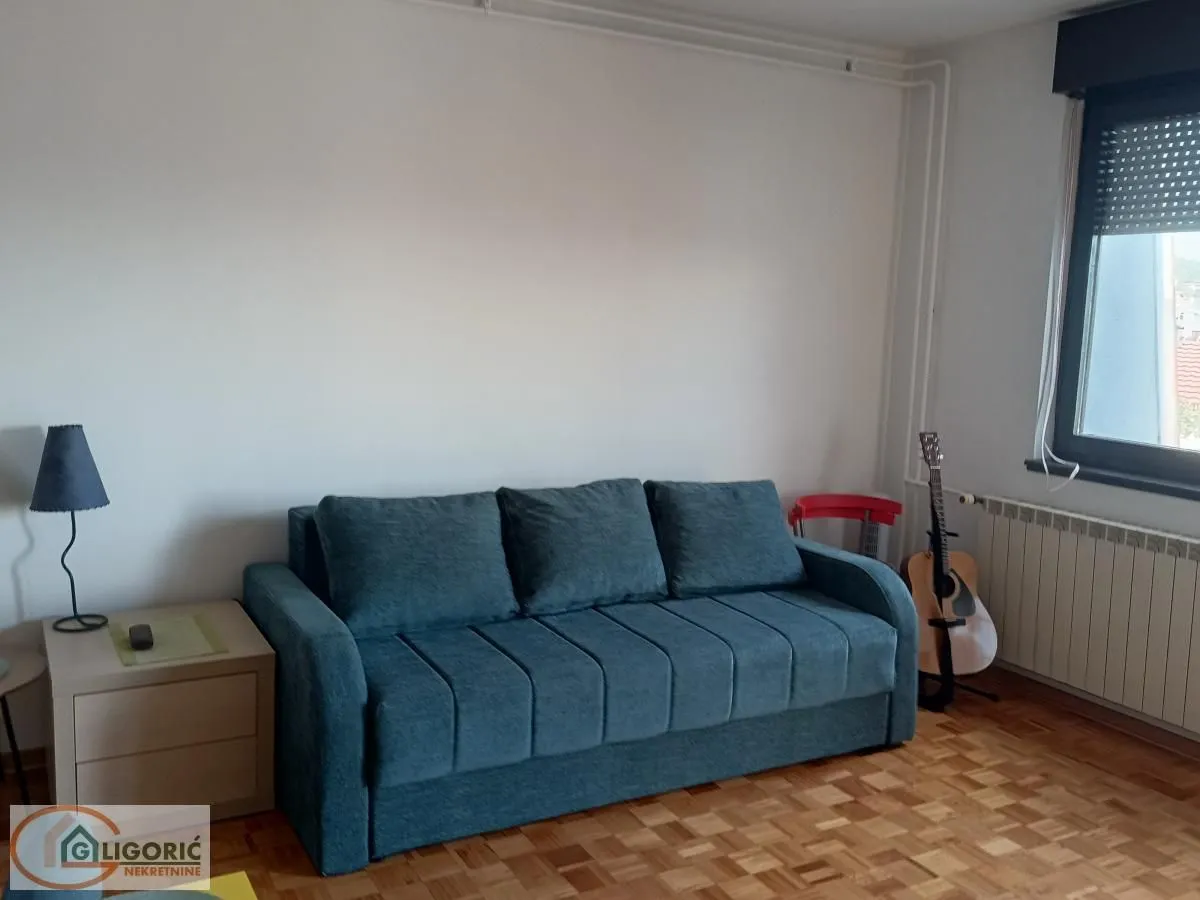 Dnevna soba sa plavim trosedom, stočićem i gitarom.