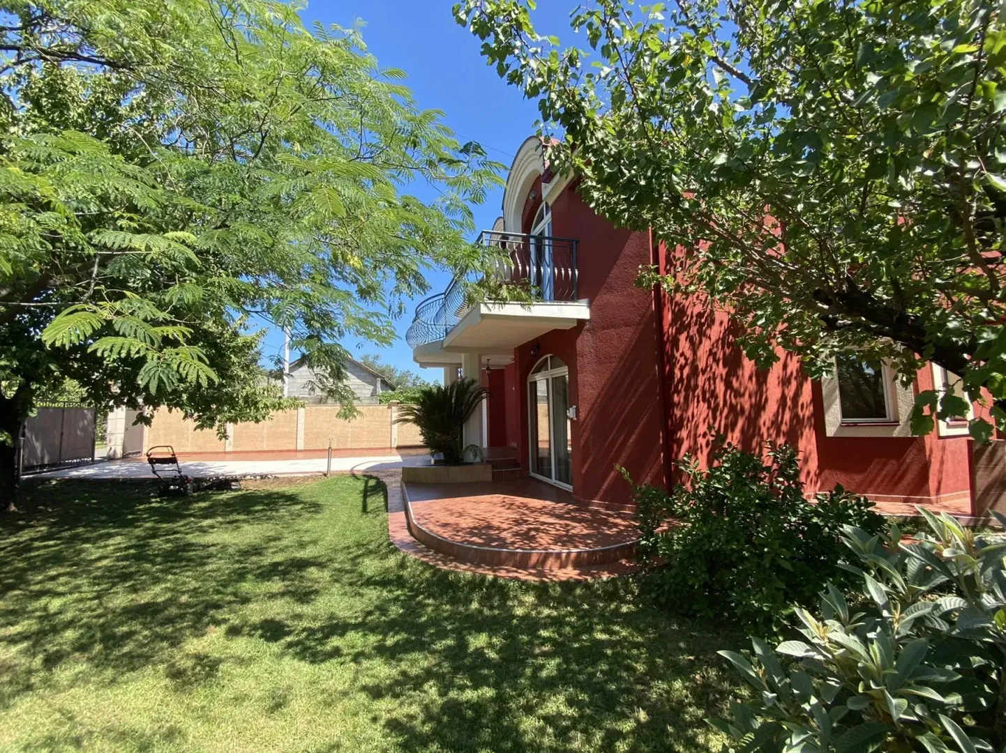 Exterior of a red house with a well-maintained yard and greenery.