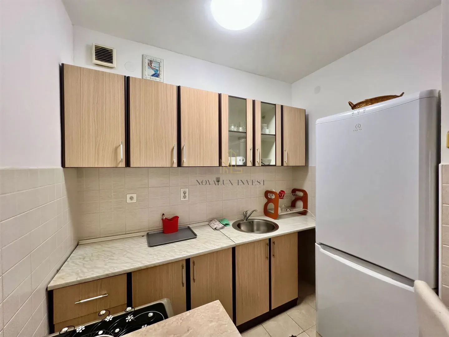 Compact kitchen with wooden cabinetry and a white refrigerator.