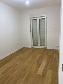 Empty room with light wooden flooring and balcony doors. - image 3