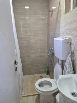 Small tiled bathroom equipped with a toilet, sink, and shower. - image 6