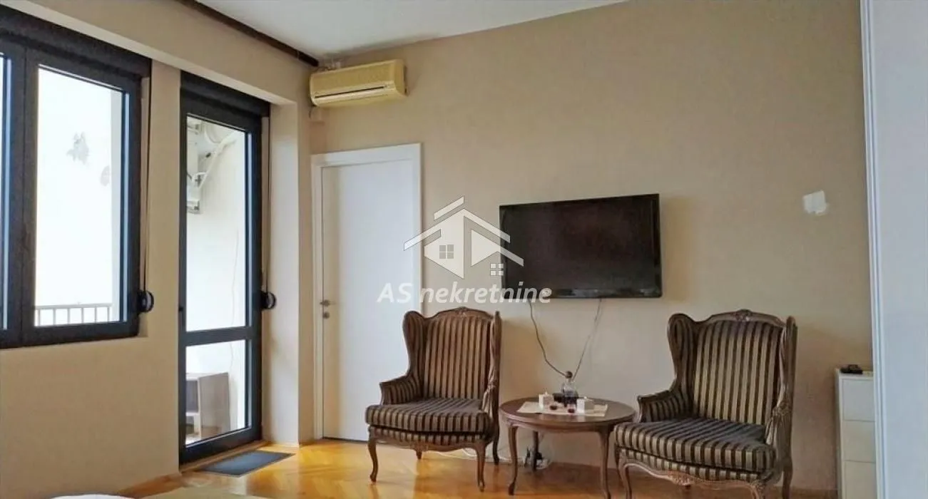 Living room with armchairs, a small table, and a wall-mounted TV.