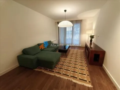 Living room with a green sectional sofa and a rug. - image 3