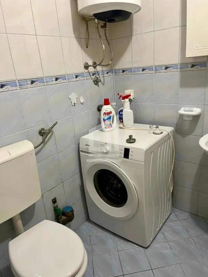 Bathroom equipped with a toilet, washing machine, and wall-mounted water heater.