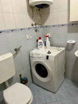 Bathroom equipped with a toilet, washing machine, and wall-mounted water heater. - image 6