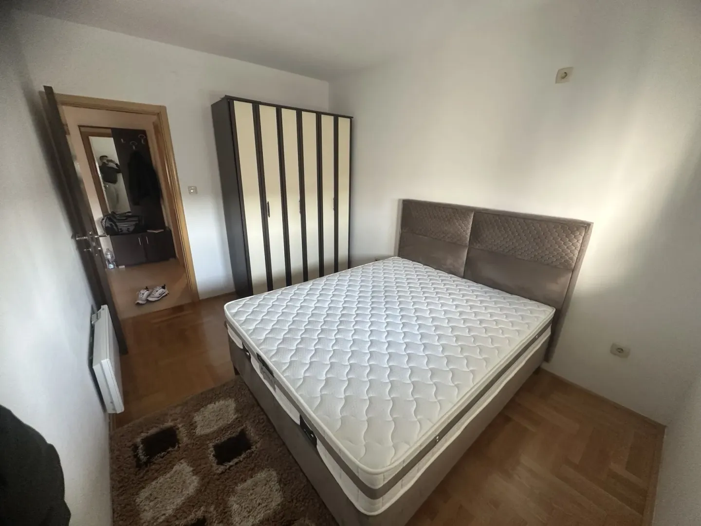 A simply furnished bedroom featuring a large bed and a three-door wardrobe.
