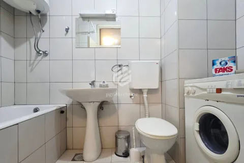 Smaller bathroom with a bathtub, washbasin, toilet, and washing machine. - image 5