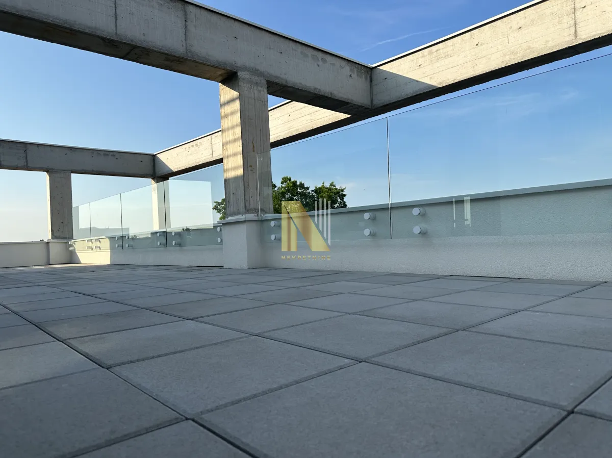 Large spacious terrace with a glass railing and concrete structure.