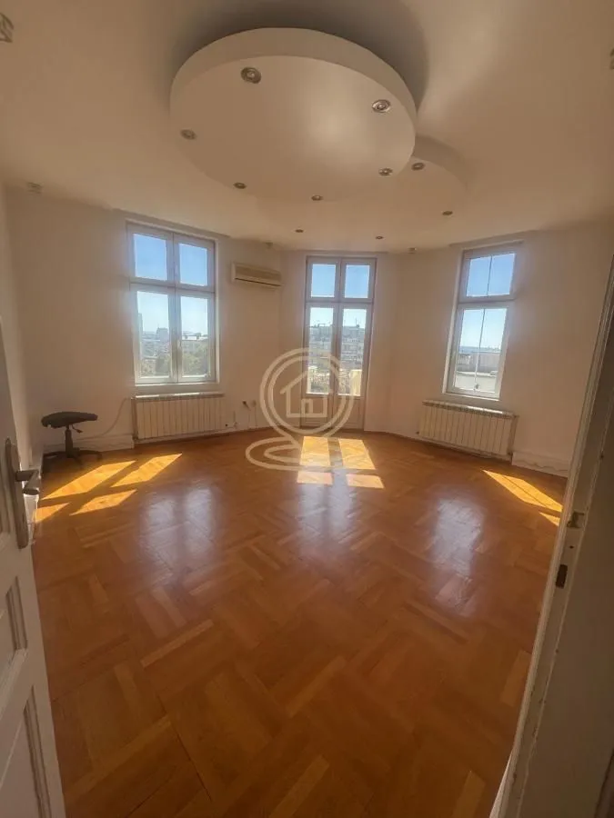 Empty living room with parquet flooring and a suspended ceiling with lighting.