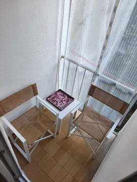 Manji balkon opremljen sa dva stolica i malim stočićem. - image 2