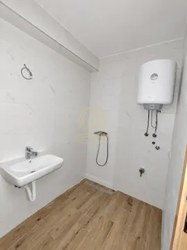 Kupatilo obloženo svetlim pločicama sa umivaonikom i bojlerom. - image 7