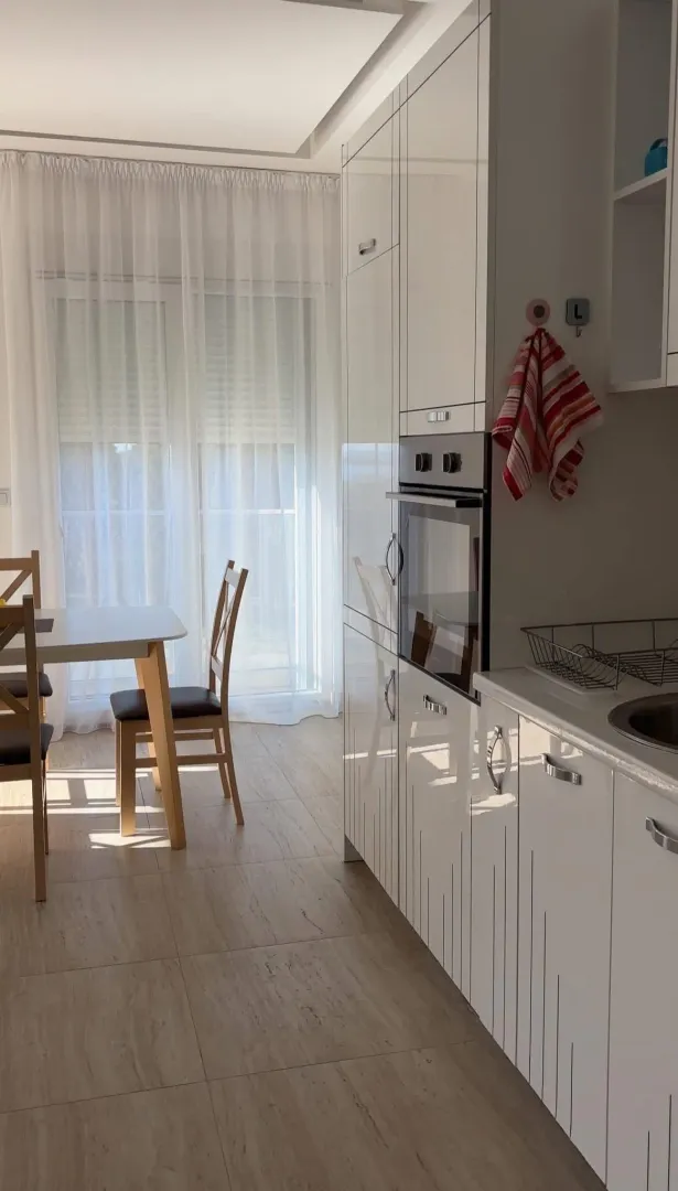 Modern kitchen with white cabinetry and a dining area by the window.