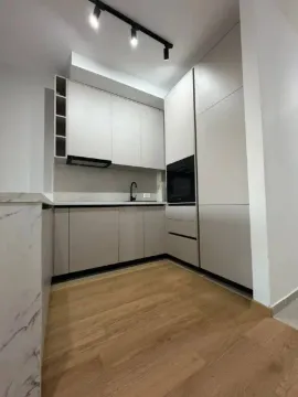 Modern kitchen with light cabinetry and wooden flooring. - image 4