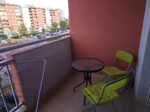 Covered balcony with a table and two chairs and a view of the neighborhood. - image 7