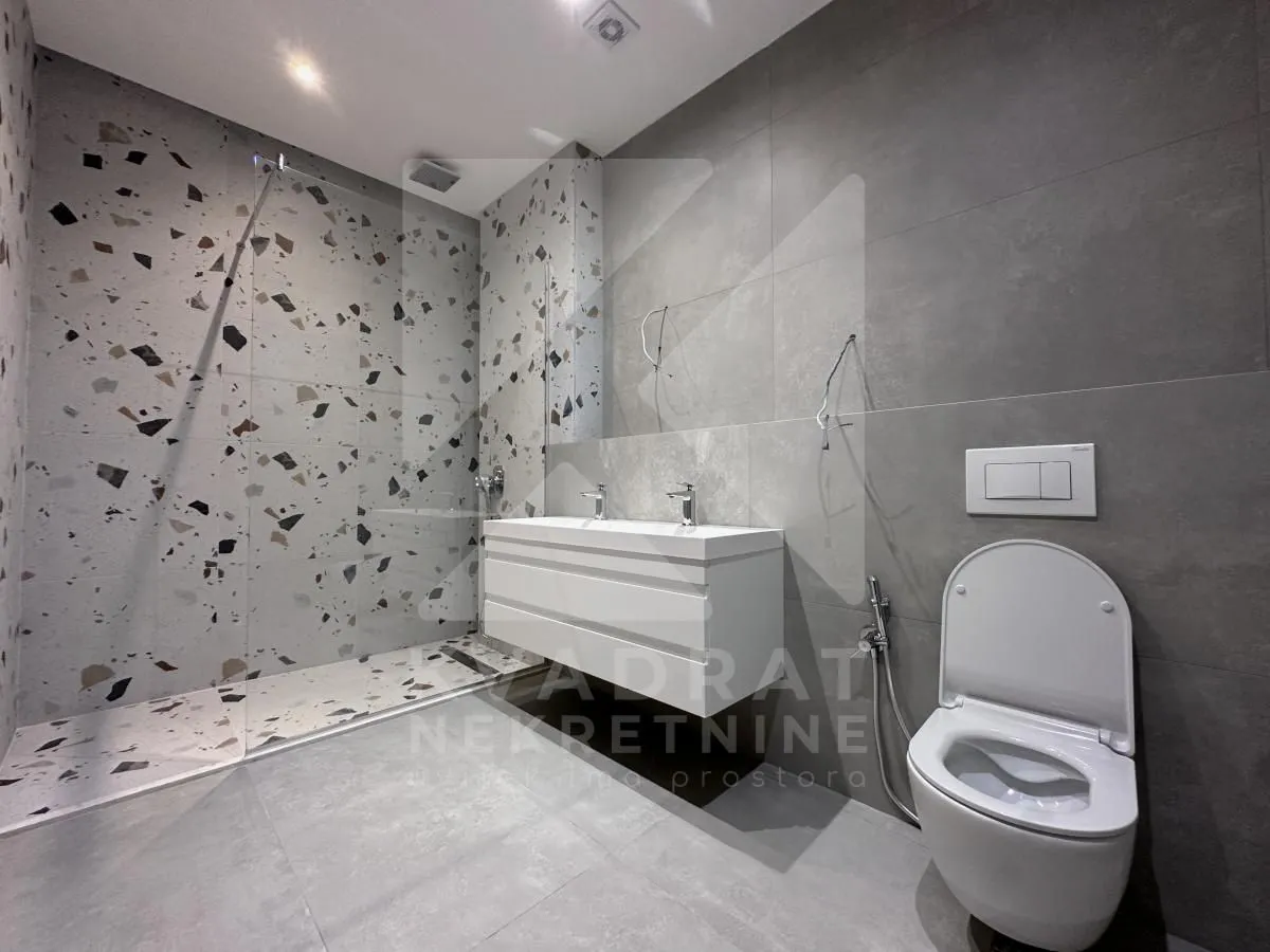 Modern bathroom equipped with a walk-in shower, white washbasin, and toilet.