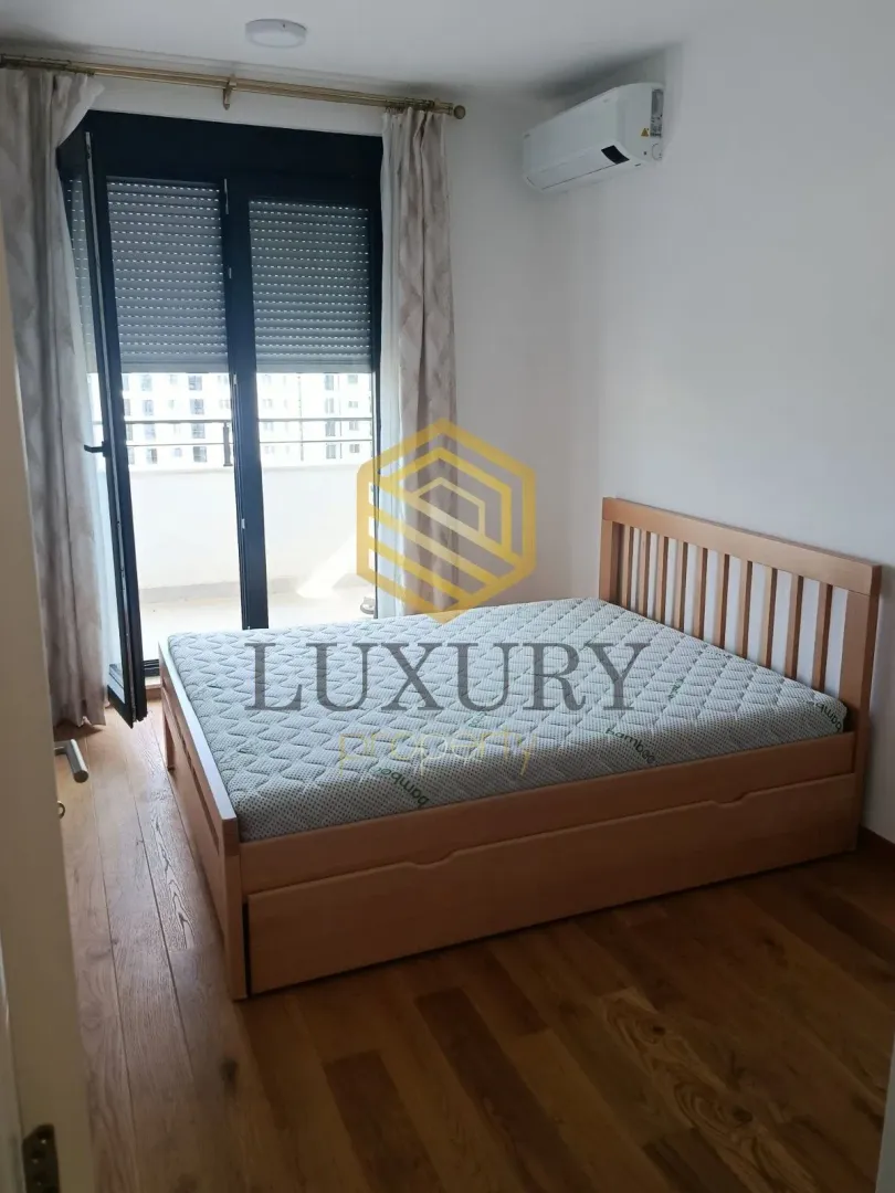 Bedroom with a double bed, wooden floor and access to the terrace.