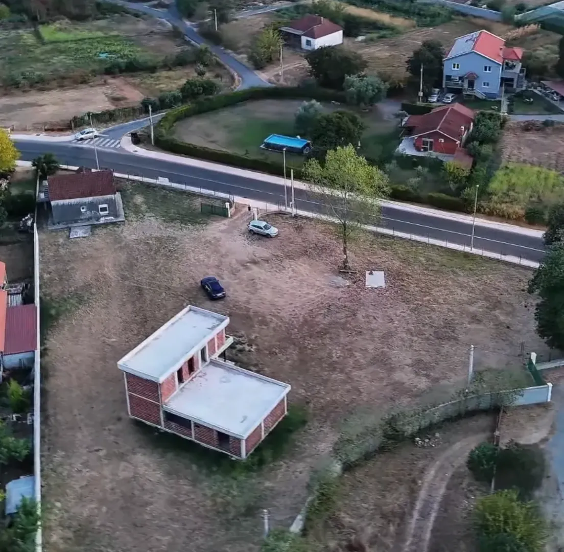 Pogled iz vazduha na plac sa objektom u izgradnji i okolnim kućama.