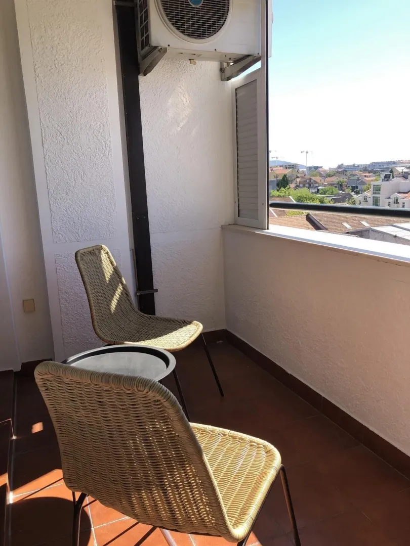 Terasa sa dvije pletene stolice i pogledom na grad.