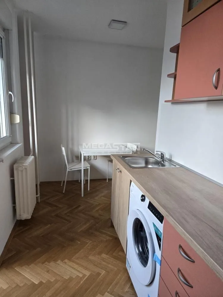 Smaller kitchen with a sink, washing machine, and dining table.