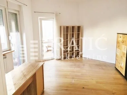 Living room with wooden flooring, shelving unit, and access to the terrace.