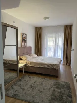 Uređena spavaća soba sa bračnim krevetom, garderoberom i prozorom sa zavjesama. - image 2