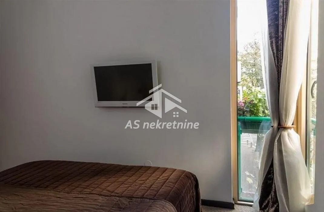 Bedroom with a bed, wall-mounted TV, and access to the terrace.