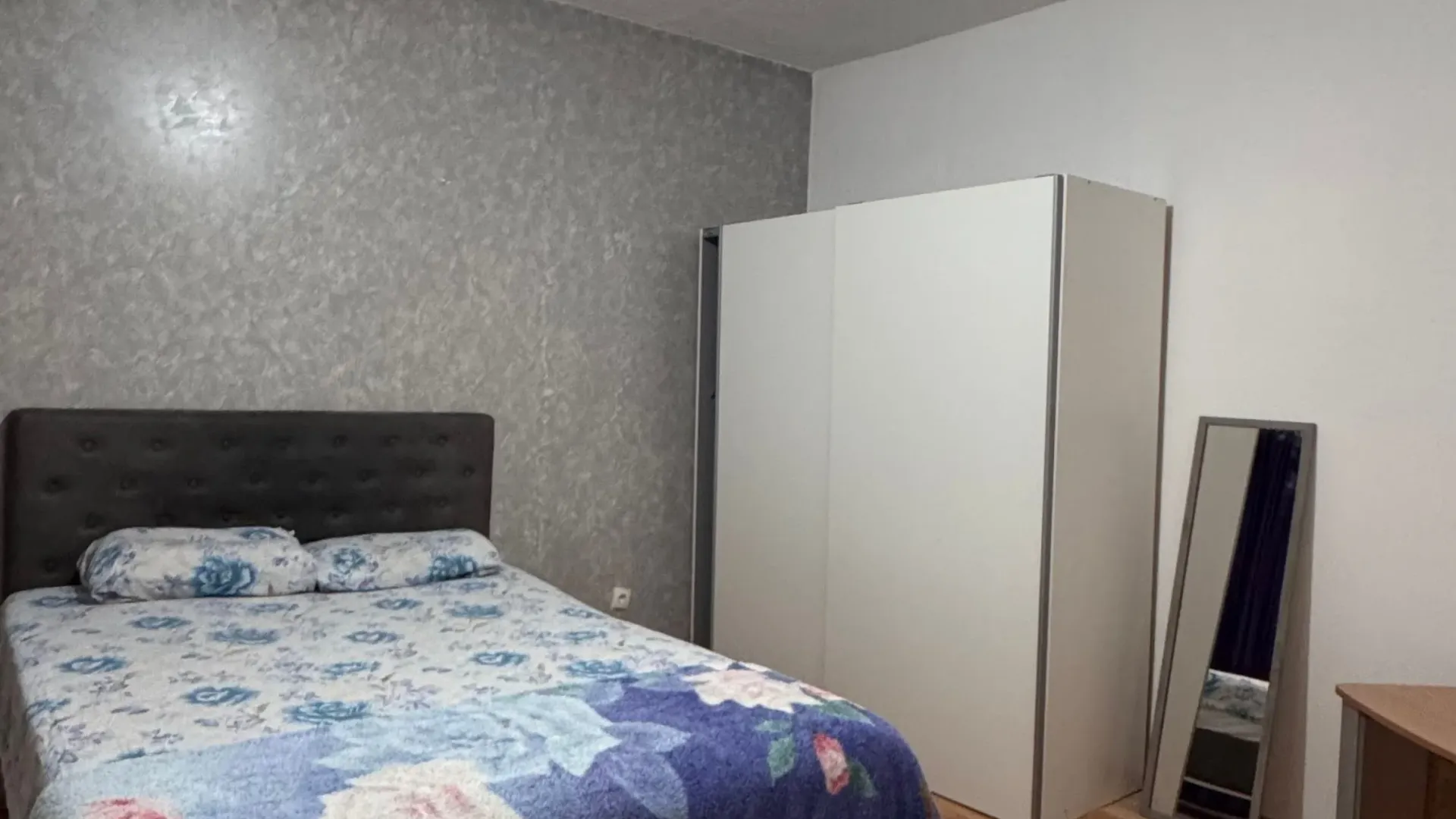 Furnished bedroom with a double bed, wardrobe, and mirror.