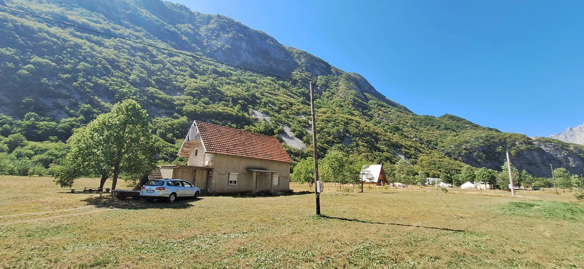 Pogled na kuću sa dvorištem u podnožju planine.