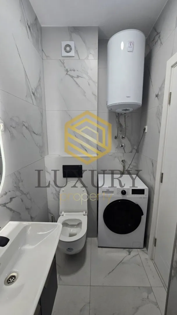 Modernly equipped bathroom with sanitary fixtures and a washing machine.