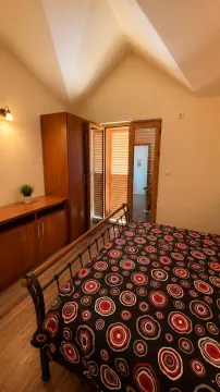 Spavaća soba sa bračnim krevetom, drvenim ormarom i izlazom na terasu. - image 10