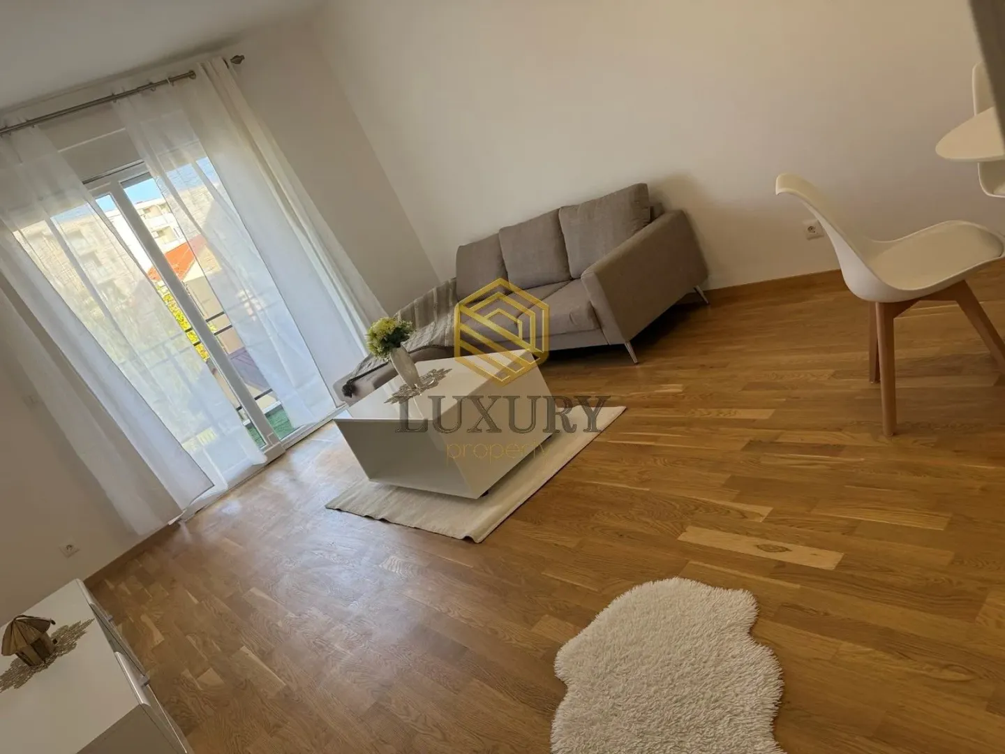 Living room with sofa, coffee table, and hardwood flooring.