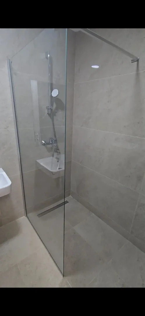 Modern bathroom with a walk-in shower and glass partition.