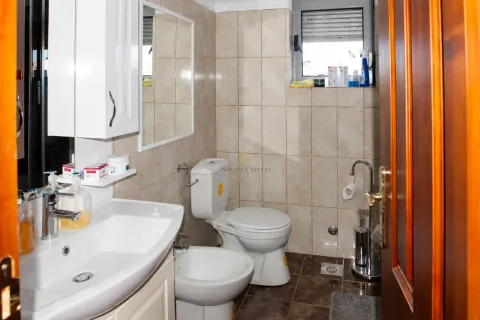 A compact bathroom with a washbasin, toilet, bidet, and tiled walls. - image 7