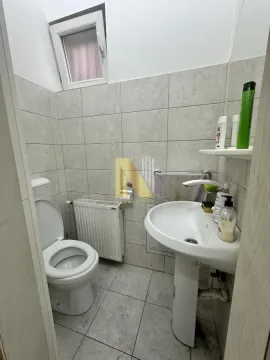 Smaller bathroom with a sink, toilet, and tiled walls. - image 7