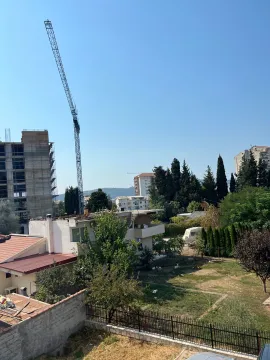 Pogled iz objekta na okolne zgrade, gradilište i zelenilo. - image 7