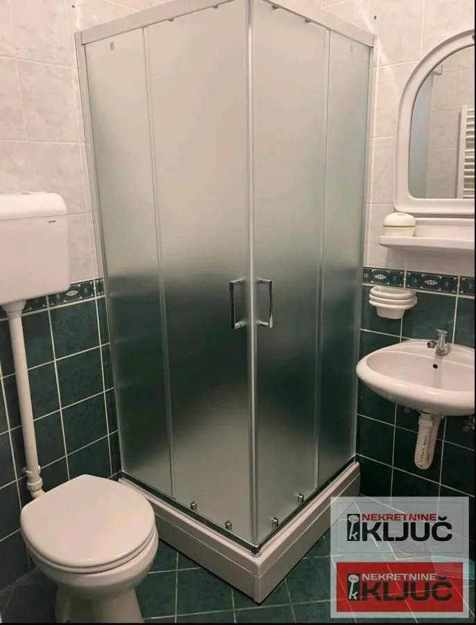 Kupatilo opremljeno tuš kabinom, umivaonikom i wc šoljom.