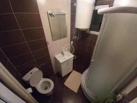 Bathroom equipped with a shower cabin, washbasin, and toilet with brown wall tiles. - image 12