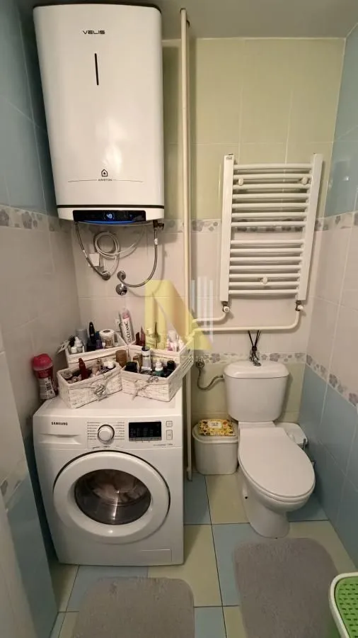 Manje kupatilo sa WC šoljom, veš mašinom i bojlerom.