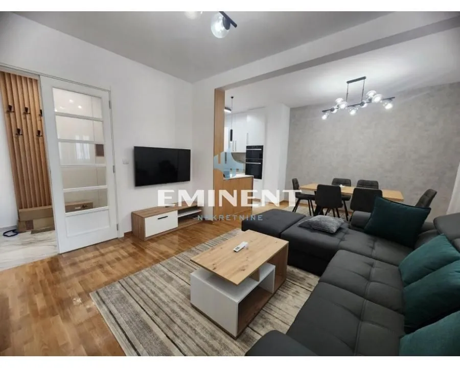 Living room with a sofa, TV, and an adjoining dining area.