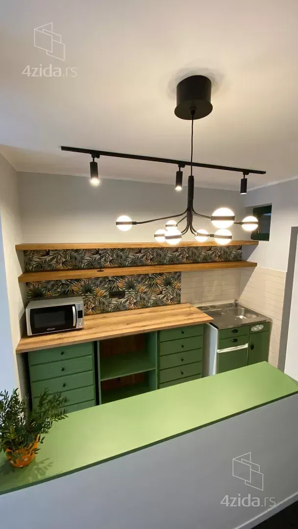 Small green kitchen with wooden countertops and hanging shelves.