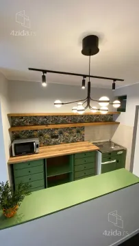 Small green kitchen with wooden countertops and hanging shelves. - image 3