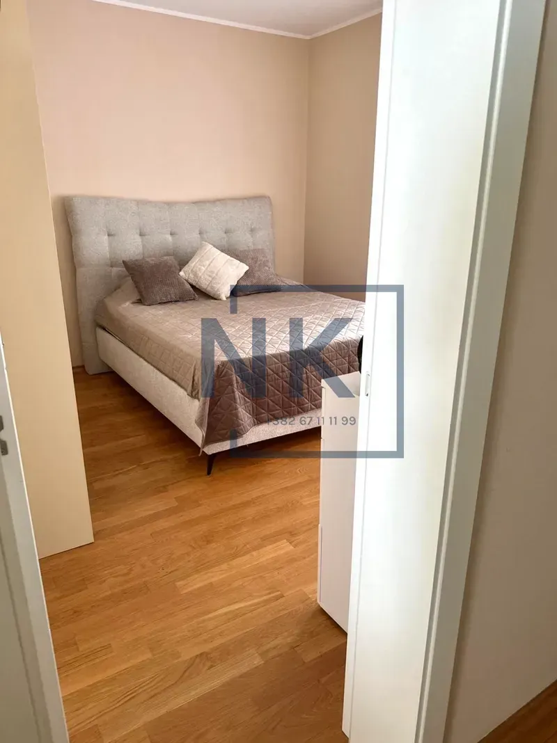 View from the hallway into a bedroom with a double bed and hardwood flooring.