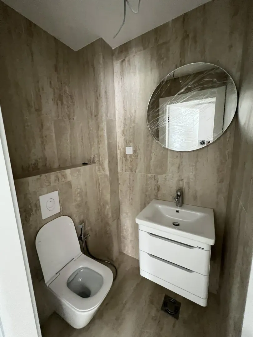 Novo kupatilo sa modernim sanitarijama i bež pločicama.