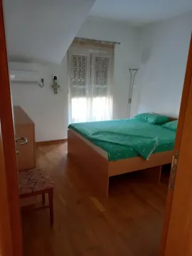 Spavaća soba sa bračnim krevetom, drvenim podom i prozorom. - image 8