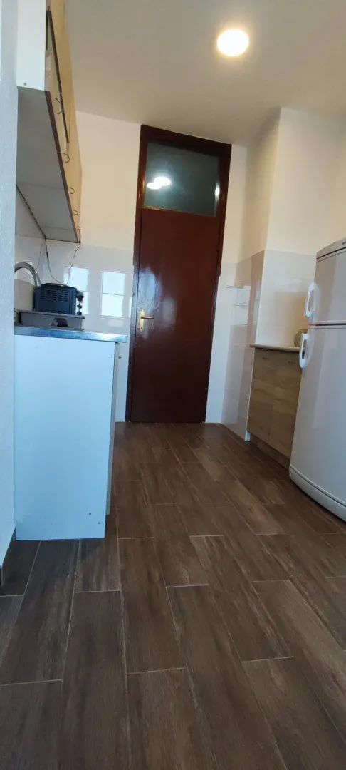 A simple kitchen with tiled flooring and wooden cabinets.