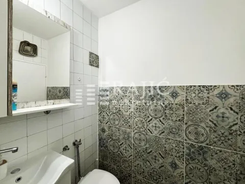 Smaller bathroom with a sink, mirror, and patterned tiles. - image 11