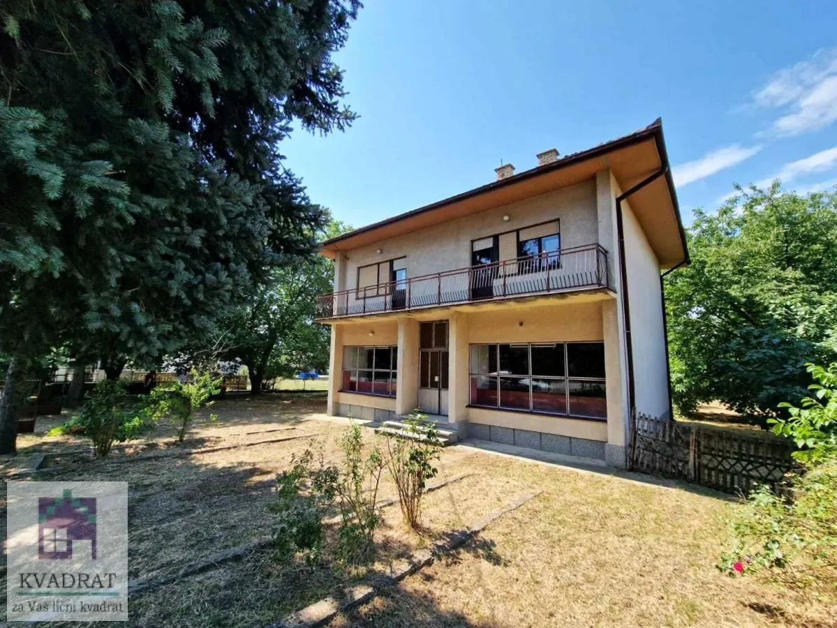 Pogled na dvorište i spoljašnjost kuće sa balkonom.