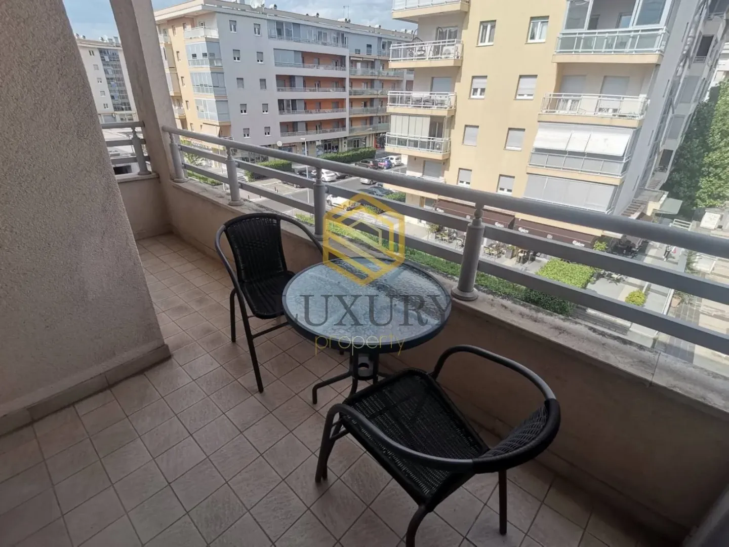 Furnished balcony with a table and two chairs and a city view.