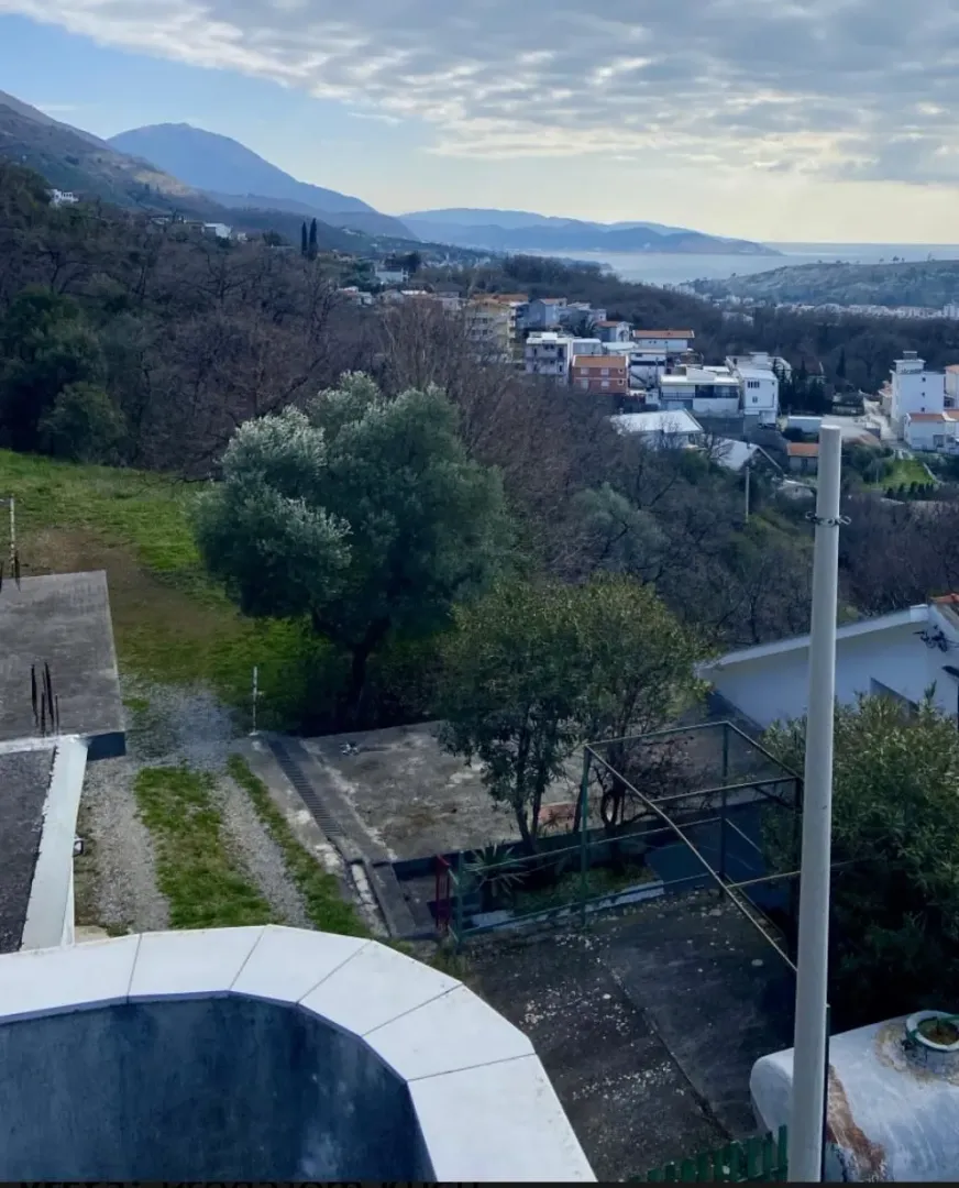 View from the terrace overlooking the settlement, greenery, and the sea in the distance.