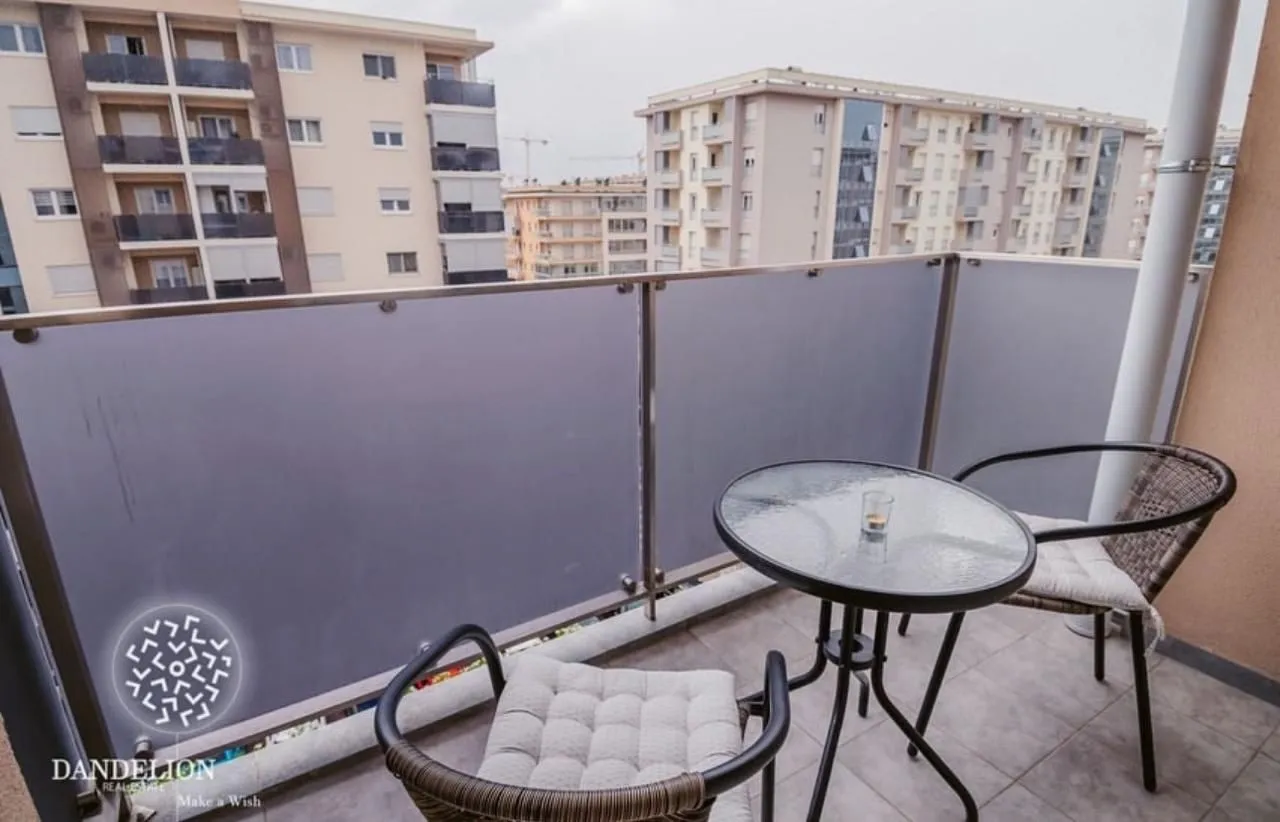 Namješten balkon sa stolom i stolicama i pogledom na zgrade.